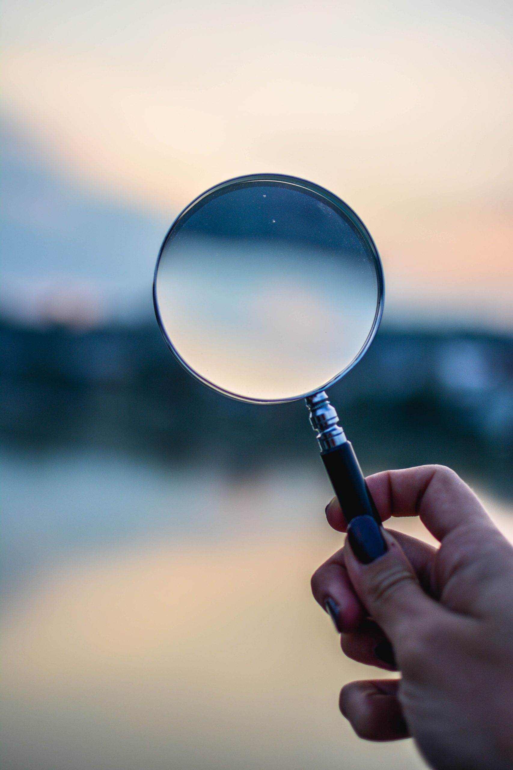 magnifying glass held up during sunset